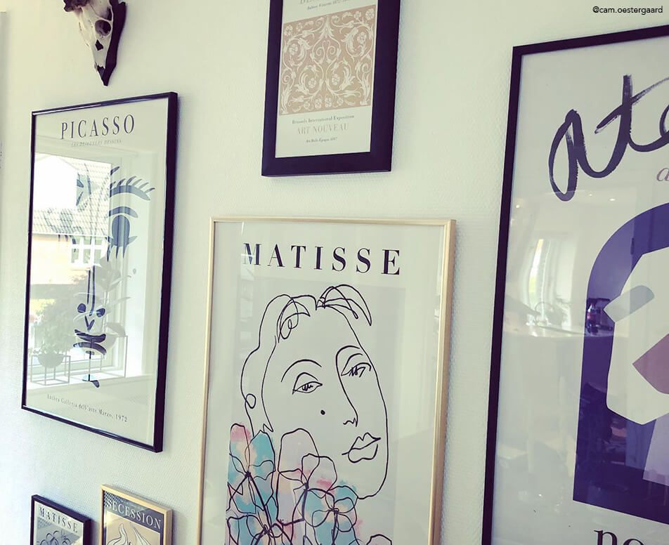 Bilderwand mit schwarzen Rahmen und Goldrahmen