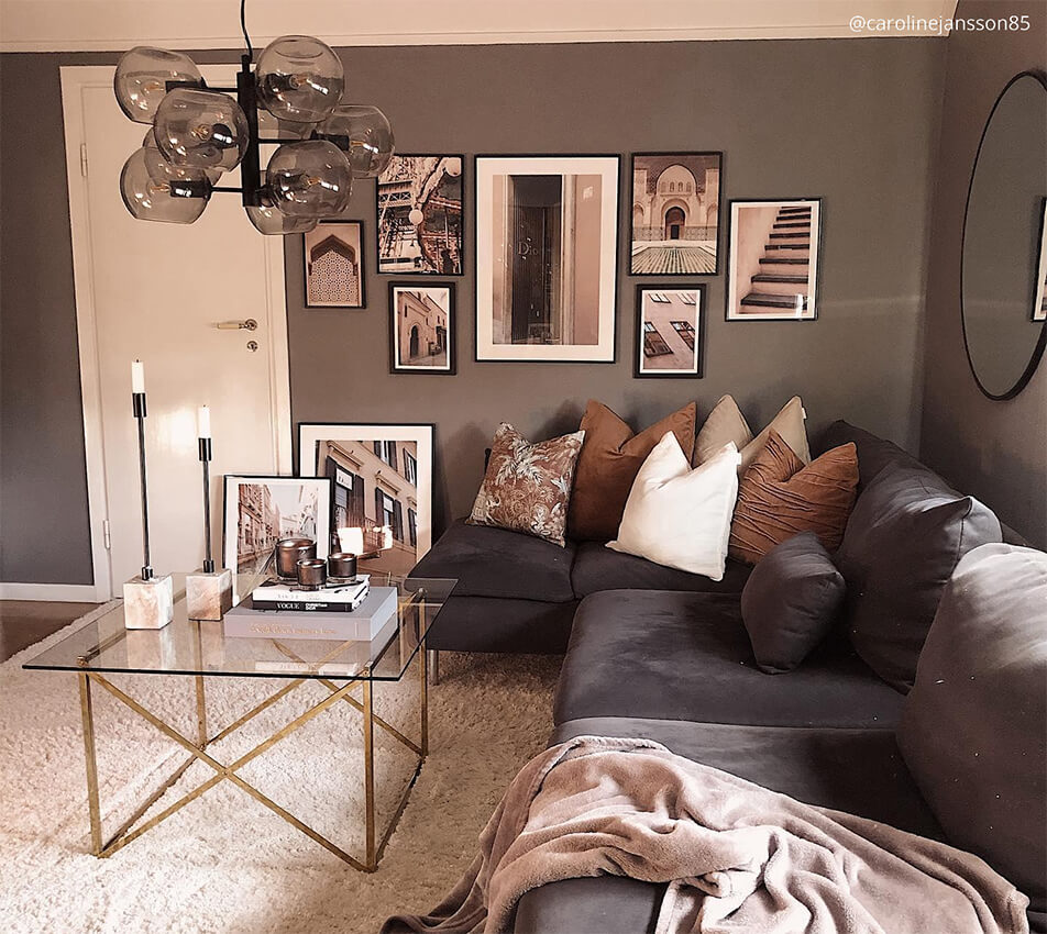 Wohnzimmer in dunkleren Erdtönen - graues Samtsofa, schwarze Bilderrahmen, Bubbel-Lampe, runder Spiegel